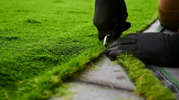 a person installing artificial turf and cutting it using a knife