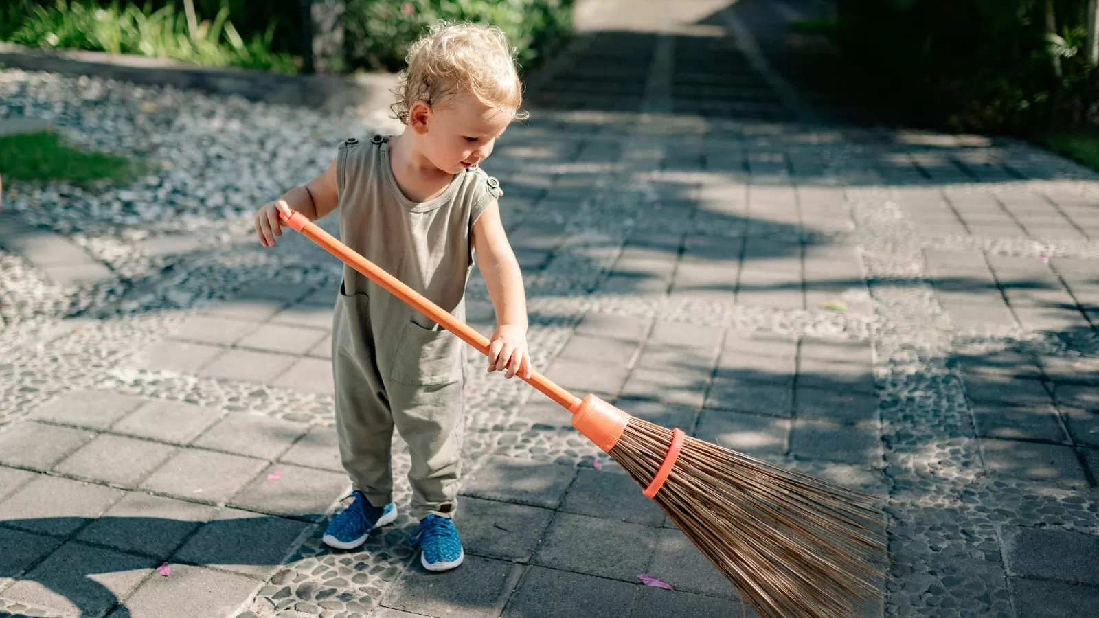 a child sweeps up a cement patio