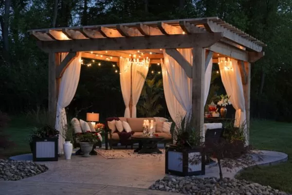A lovely gazebo and wicker sofa with string lights illuminating and highlighting the sofa