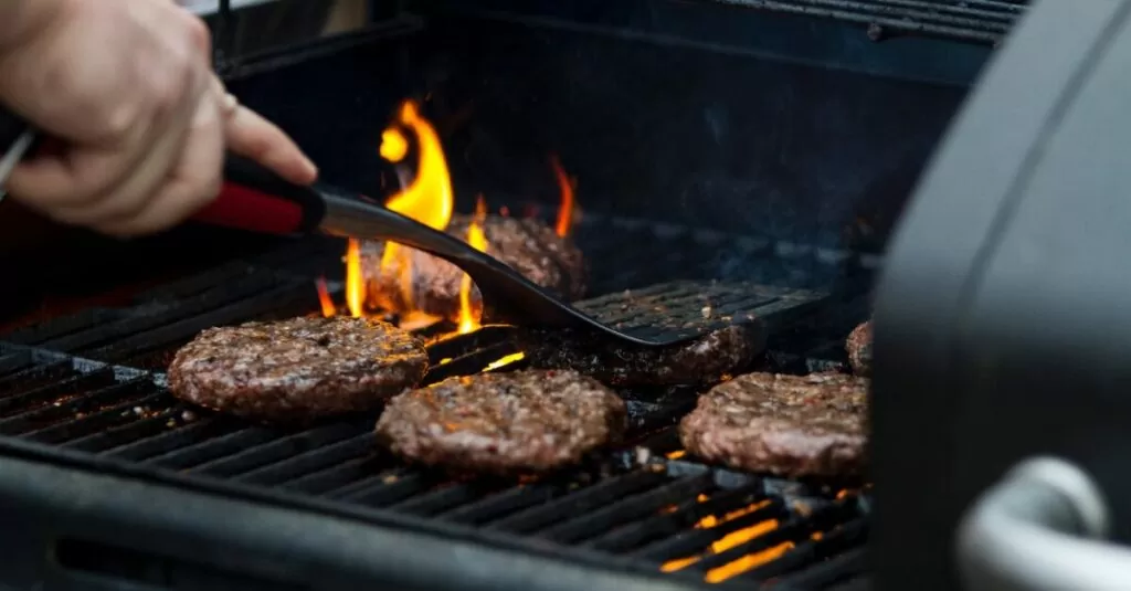 person grilling hamburger patties