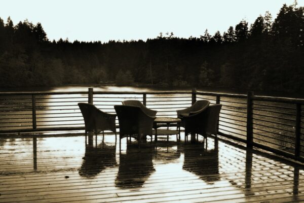 grayscale photo of two wooden chairs on wooden dock