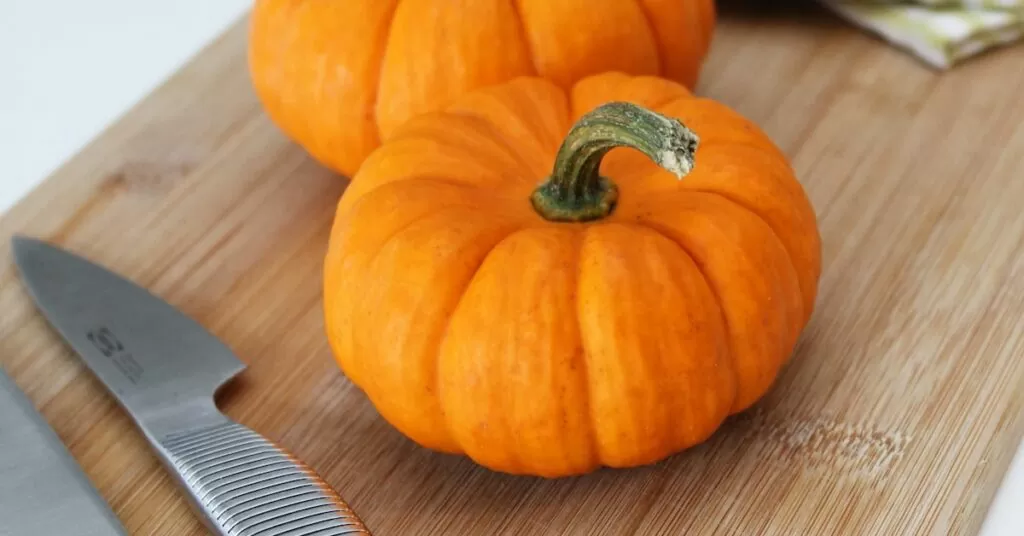 selective focus photography of two pumpkins placed on chopping board