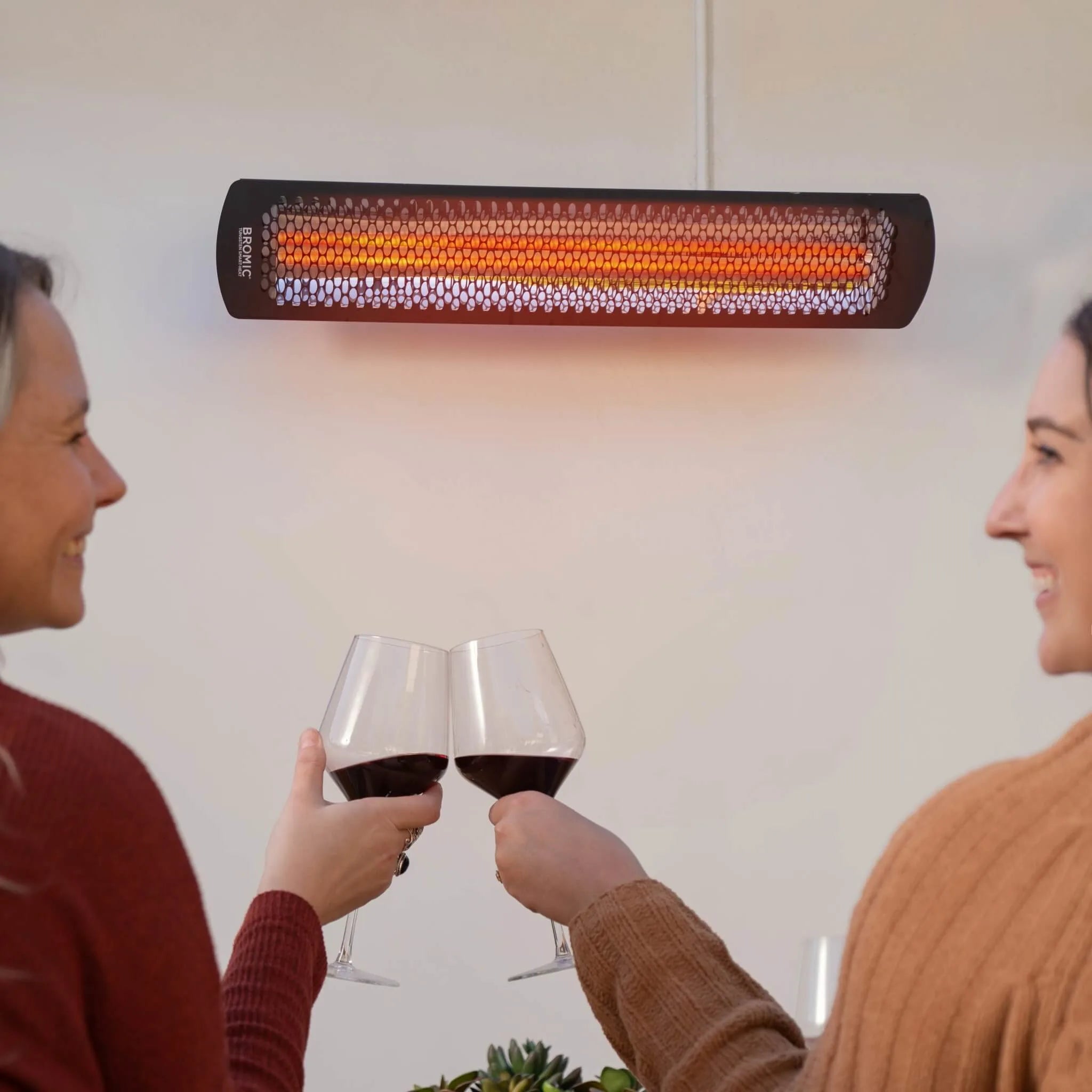 Cozy residential patio with Bromic Tungsten Electric Smart-Heat heater installed above an outdoor dining area, offering gentle radiant warmth for casual gatherings.